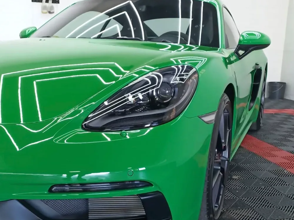 Porsche verde com a pintura vitrificada refletindo as luminárias do estúdio