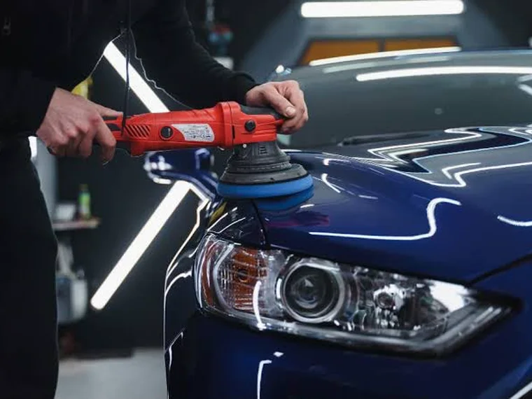 Politriz com boina sobre o capô azul de um carro, sob a luz do estúdio