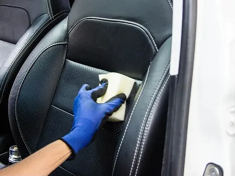 Limpeza de banco de couro preto com esponja e luva